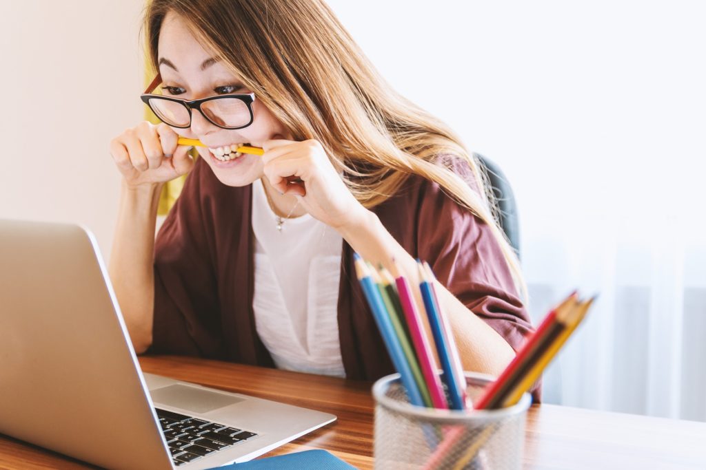 Frustrated woman at laptop biting pencil